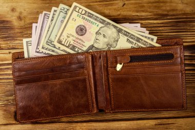 Ahşap masanın üzerinde Amerikan doları olan açık cüzdan. Üstte görüntü