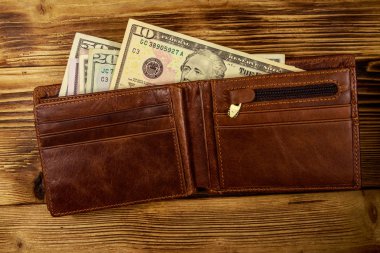 Ahşap masanın üzerinde Amerikan doları olan açık cüzdan. Üstte görüntü