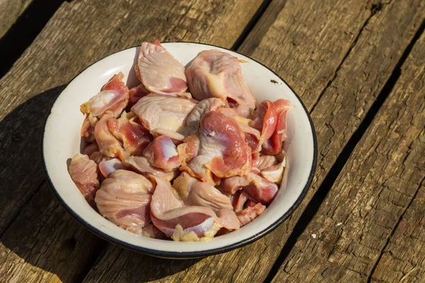 Raw chicken gizzards in metal enamelled bowl on rustic wooden table — Stock Photo, Image