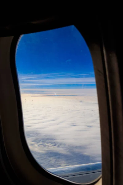 Vista do céu azul com nuvens brancas através da janela do pórtico avião voador — Fotografia de Stock