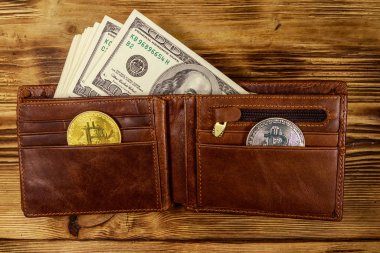 Ahşap arka plan üzerinde Amerikan yüz dolar faturaları ve bitcoins ile Cüzdan