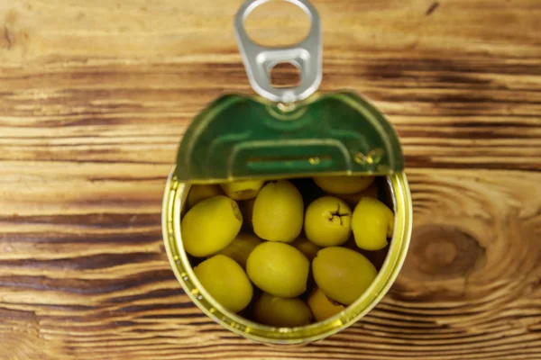 木製のテーブルの上に緑のオリーブのオープンスズ缶。トップビュー — ストック写真