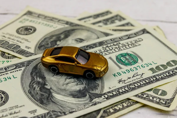 美元和微型汽车模型在白色木制背景。汽车贷款概念 — 图库照片