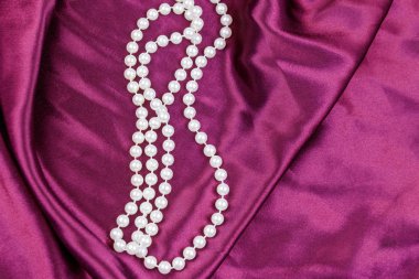 Mor saten kumaş arka planda inci kolye