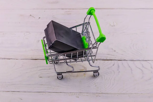 Carrito con caja negra sobre fondo de madera blanco —  Fotos de Stock