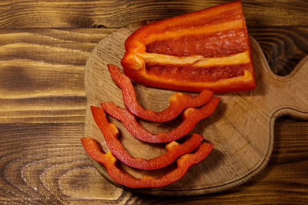 Свежий красный перец на разделочной доске на деревянном столе — стоковое фото