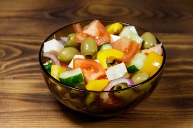 Ahşap masa üzerinde cam kapta Yunan salatası