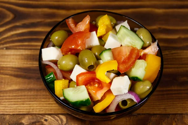 Salada grega em tigela de vidro na mesa de madeira — Fotografia de Stock