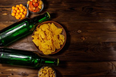 Bira şişeleri ve ahşap masada bira için çeşitli atıştırmalıklar.