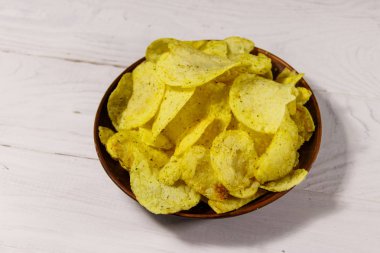 Beyaz ahşap masada patates cipsi tabağı