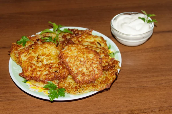 Homemade fried potato pancakes with sour cream on wooden table — Stock Photo, Image