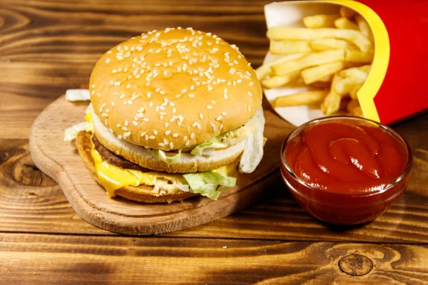 Läcker stor hamburgare med pommes frites och ketchup på träbord — Stockfoto