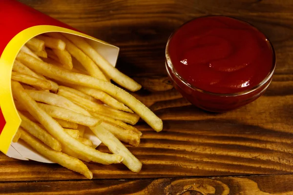 Frietjes met ketchup op houten tafel — Stockfoto