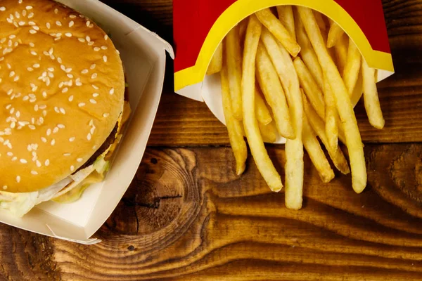 Stor hamburgare och pommes frites på träbord — Stockfoto