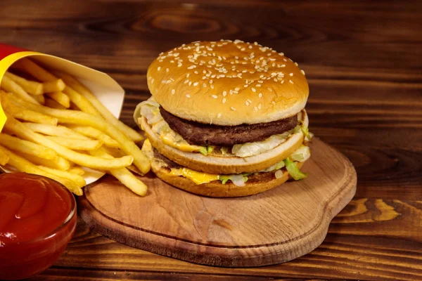 Delicioso hambúrguer grande com batatas fritas e ketchup na mesa de madeira — Fotografia de Stock