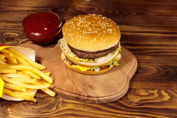 Heerlijke grote hamburger met frietjes en ketchup op houten tafel — Stockfoto
