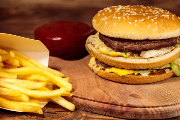 Delizioso hamburger grande con patatine fritte e ketchup sul tavolo di legno — Foto Stock
