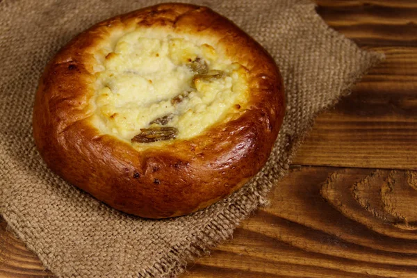 Zoete ronde broodje met kwark en rozijnen (Cheesecake) op houten tafel — Stockfoto