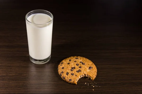 Chocolate chip cookies and glass of milk on wooden table — Stock Photo, Image
