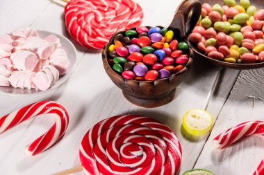 Beyaz ahşap masa üzerinde seramik kase çikolata renkli düğmesini şeker şeklinde dolu
