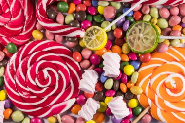 Renkli çikolata şekerlemeleri, lolipoplar, şeker kamışı ve şekerlemelerin arka planı