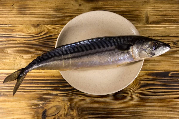 Соленая рыба-скимбер на тарелке. Целая скумбрия на деревянном столе — стоковое фото