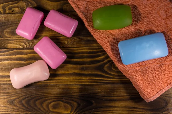 Set di sapone colorato e asciugamano su sfondo di legno — Foto Stock