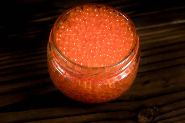 Caviar rojo en tarro de vidrio sobre mesa de madera — Foto de Stock