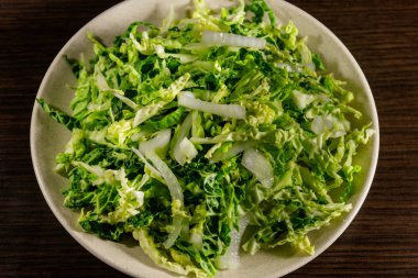 Ahşap masada lahana ve soğanlı salata.