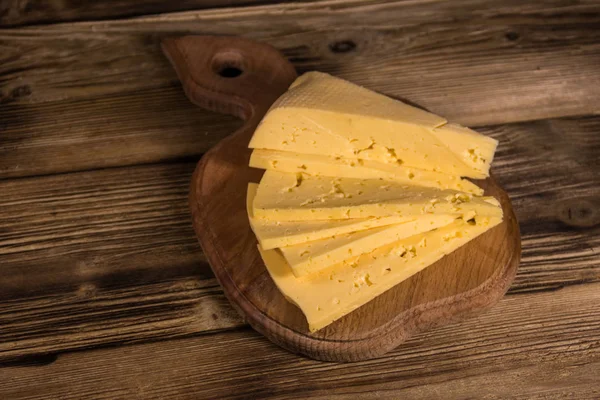 Ahşap masa üzerinde kesme tahtası üzerinde peyniri dilimlenmiş — Stok fotoğraf