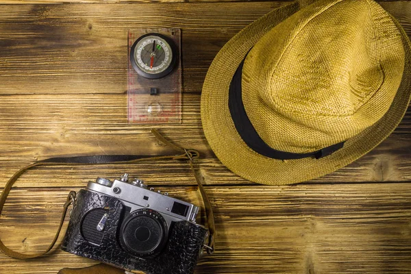 Ahşap arka plan üzerinde Pusula, şapka ve retro fotoğraf makinesi