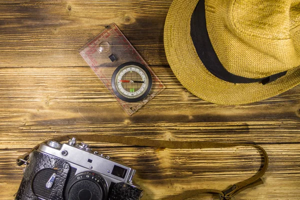 Ahşap arka plan üzerinde Pusula, şapka ve retro fotoğraf makinesi