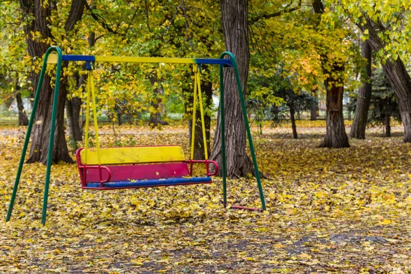 Columpio de los niños vacíos en el parque de la ciudad en otoño — Foto de Stock