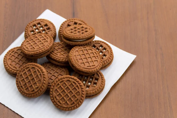 Biscotti al cioccolato con ripieno di panna sul tavolo di legno — Foto Stock