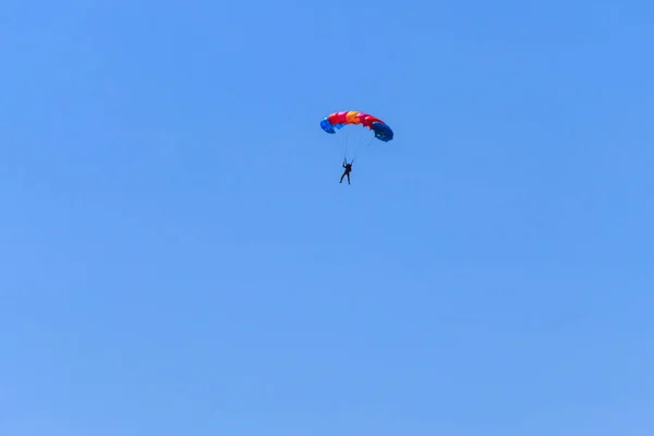 Parašutista sestupoval s padákem proti modré obloze — Stock fotografie