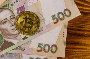 Altın bitcoin ve ahşap arka plan üzerinde beş yüz Ukrayna Grivnası faturaları