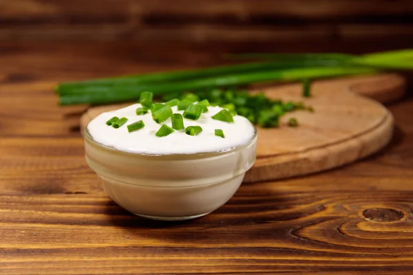 Gräddfil och grön lök på träbord — Stockfoto