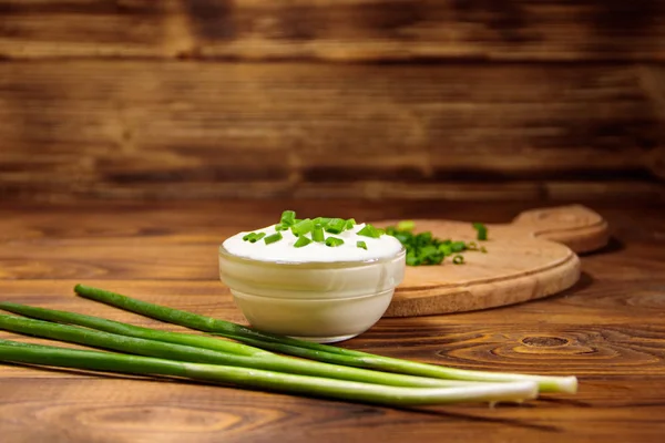 Sour cream and green onion on wooden table — Stock Photo, Image