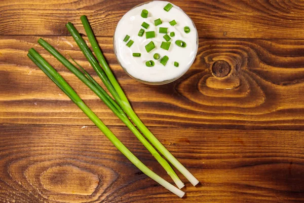 Sour cream and green onion on wooden table. Top view — Stock Photo, Image