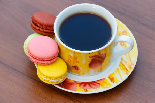 Cup of coffee with tasty colorful macarons on wooden table — Stock Photo, Image