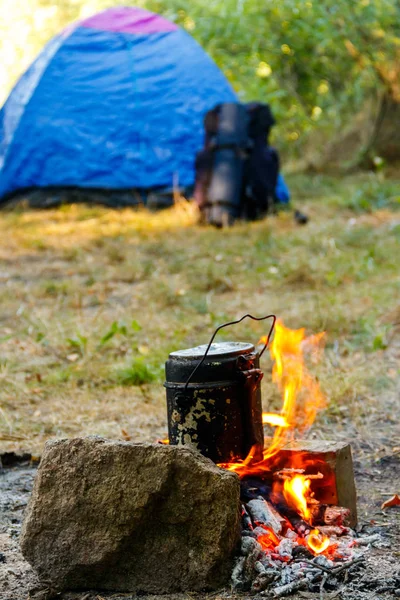 Koken op kampvuur op de camping. Tent en rugzak op achtergrond — Stockfoto