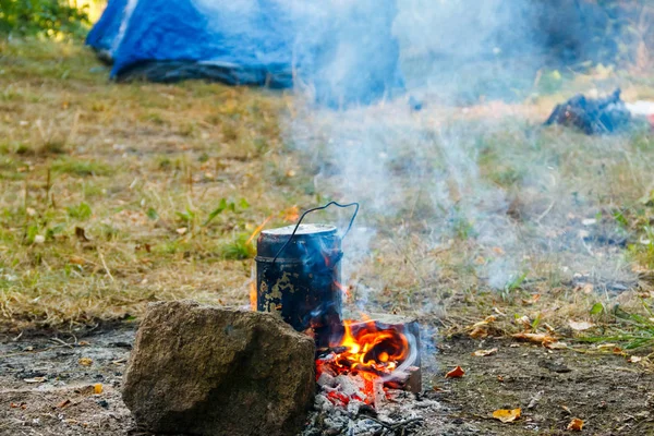 Gotowanie przy ognisku na kempingu. Namiot i plecak na tle — Zdjęcie stockowe