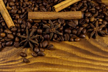 Kavrulmuş kahve çekirdekleri, tarçın çubukları ve ahşap arka planda yıldız anason.