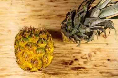 Ahşap masada ananas yaprakları ve meyvesi. Üstte görüntü