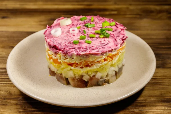 Salată tradițională rusă "Herring sub o haină de blană" (shuba) pe masă de lemn. Salată stratificată cu hering, sfeclă, morcovi, ceapă, cartofi și ouă — Fotografie, imagine de stoc