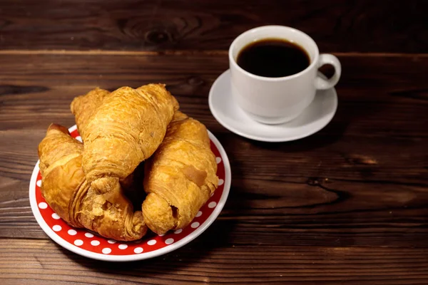 Tasse de café et assiette avec croissants frais sur table en bois — Photo