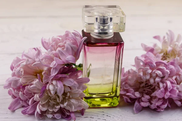 Femmes parfum avec des fleurs sur fond blanc en bois — Photo