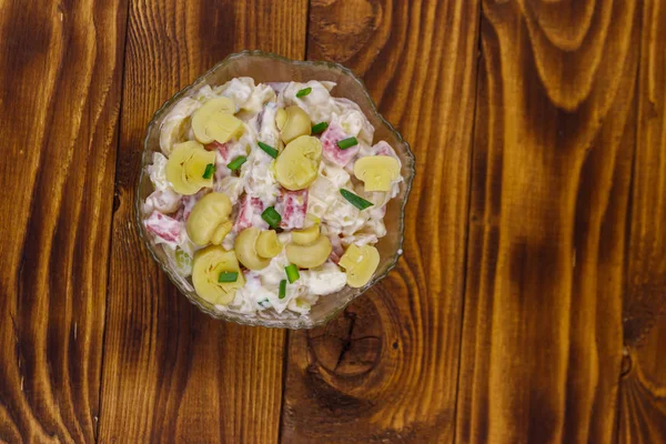 Картофельный салат с маринованными грибами, колбасой, луком и майонезом на деревянном столе — стоковое фото