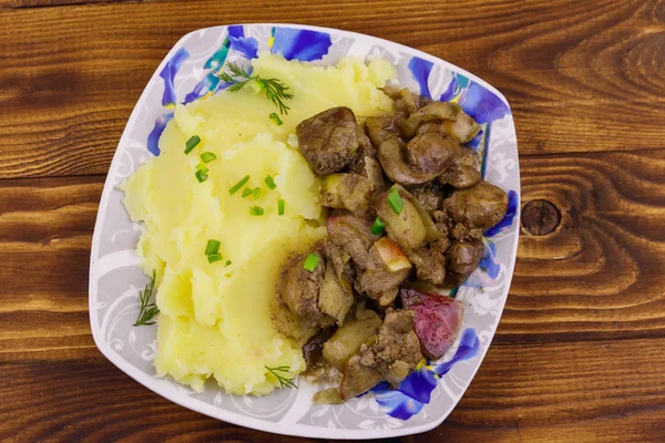 Purée de pommes de terre au foie de poulet cuit avec pomme et oignon sur une table en bois — Photo