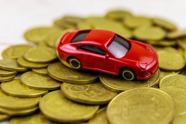 Beyaz ahşap arka plan üzerinde altın sikke yığını üzerinde Minyatür araba modeli